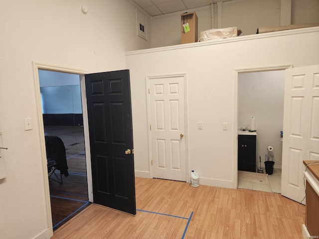 bedroom with baseboards, a high ceiling, a paneled ceiling, and light wood-style floors