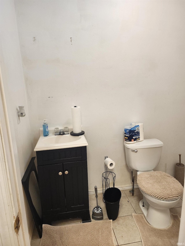 half bath with baseboards, vanity, toilet, and tile patterned floors