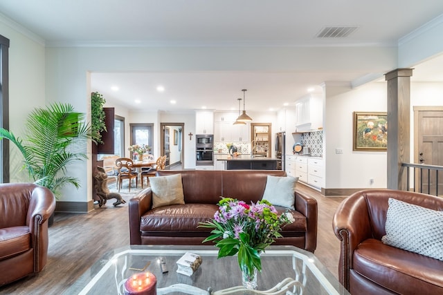 living room with visible vents, crown molding, and ornate columns