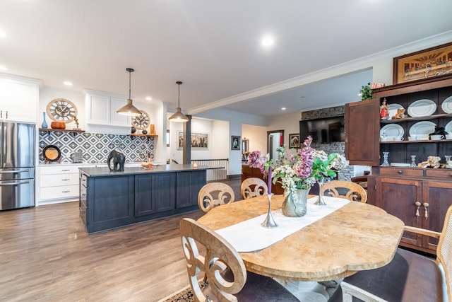 dining area featuring light wood finished floors, ornamental molding, and recessed lighting