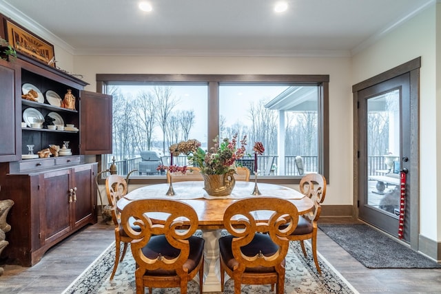 dining area with baseboards, crown molding, and light wood finished floors