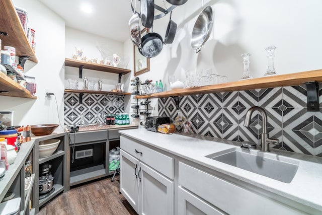 kitchen with wood finished floors, a sink, light countertops, backsplash, and open shelves