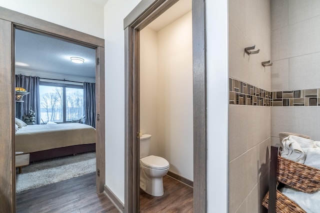 ensuite bathroom with baseboards, ensuite bathroom, toilet, and wood finished floors