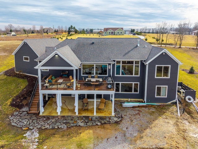 rear view of property with a patio area, stairs, a deck, and roof with shingles