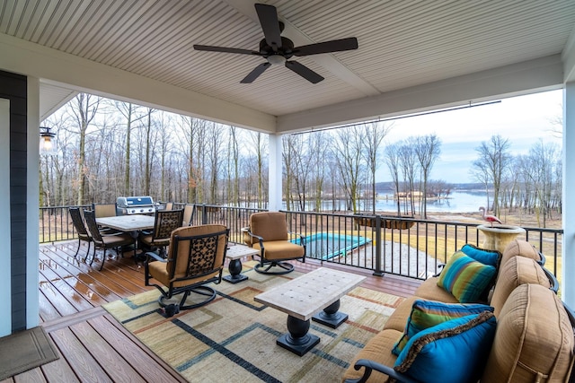 sunroom featuring ceiling fan and a water view