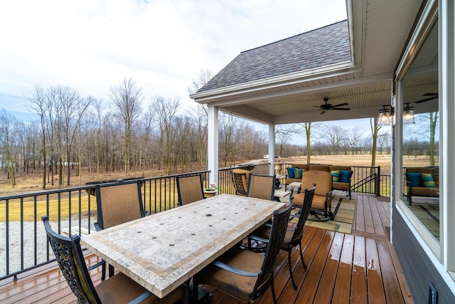 wooden terrace with outdoor dining area and a ceiling fan