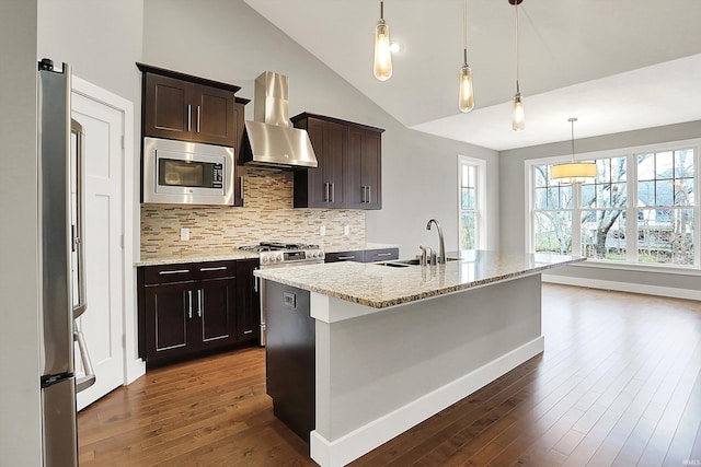 kitchen with decorative backsplash, wall chimney exhaust hood, appliances with stainless steel finishes, dark wood-style flooring, and a sink