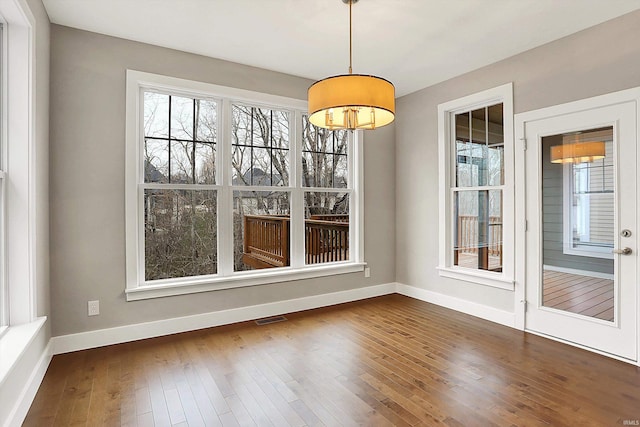 unfurnished dining area with dark wood-style flooring, visible vents, and baseboards