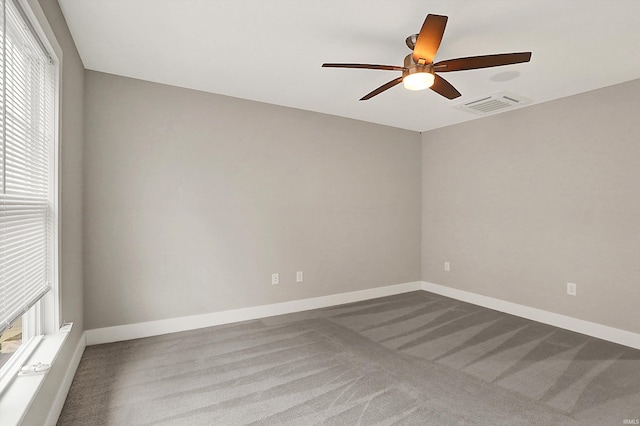 carpeted spare room featuring a ceiling fan, visible vents, and baseboards