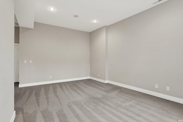 empty room with dark colored carpet, recessed lighting, and baseboards