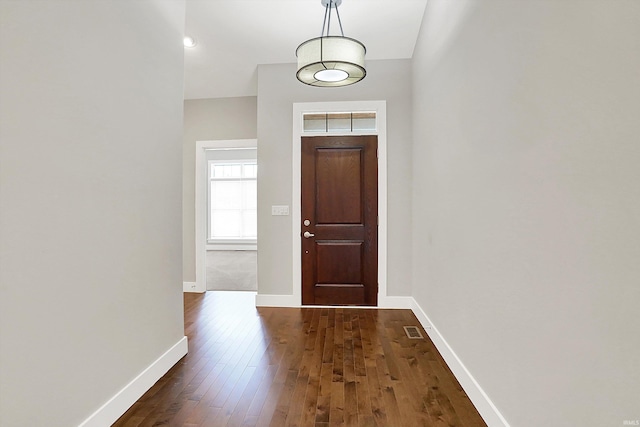 foyer entrance with baseboards, visible vents, and dark wood finished floors