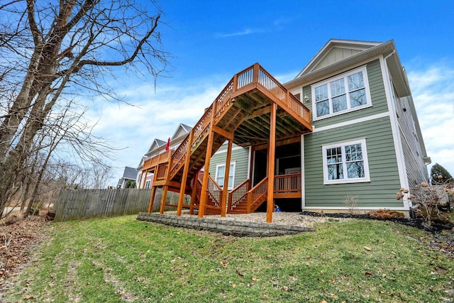 back of property featuring a deck, a yard, stairway, and fence