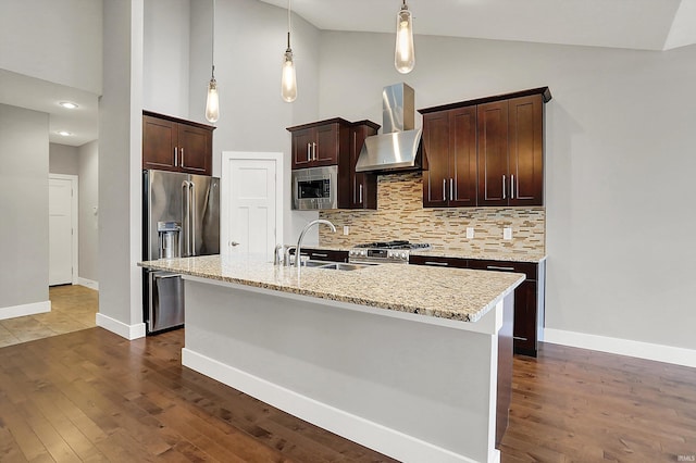 kitchen featuring decorative backsplash, appliances with stainless steel finishes, dark brown cabinetry, a sink, and wall chimney range hood