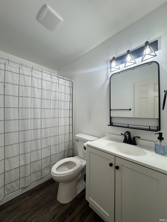 bathroom featuring visible vents, toilet, vanity, a textured ceiling, and wood finished floors