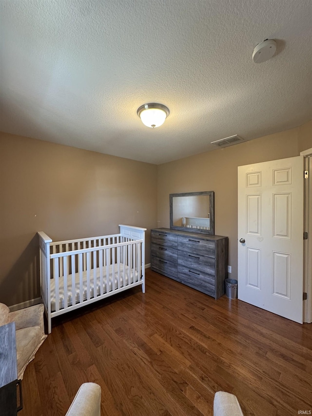 unfurnished bedroom with a textured ceiling, visible vents, and wood finished floors