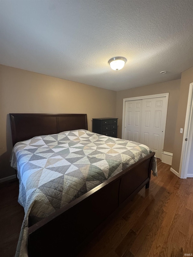 bedroom featuring dark wood-style floors, a closet, a textured ceiling, and baseboards