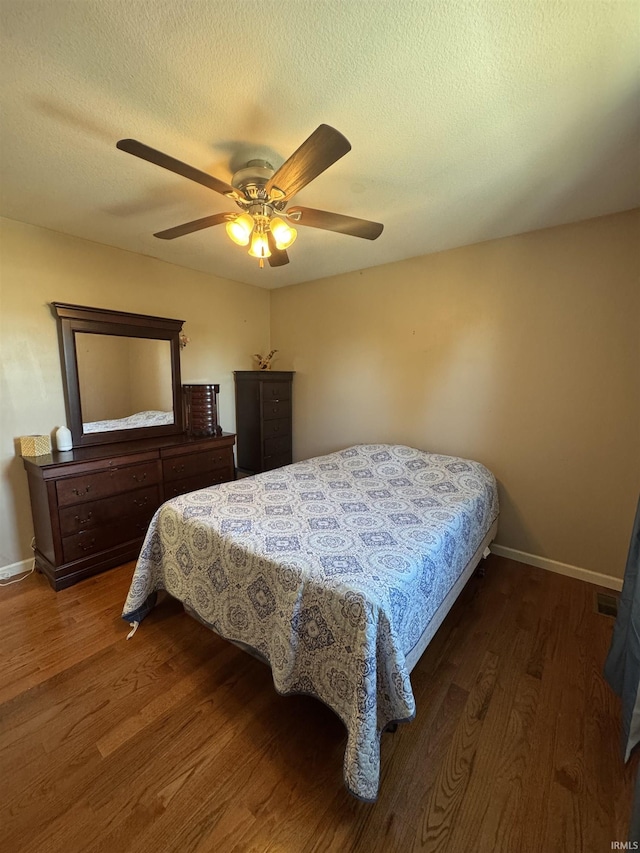 bedroom with dark wood-style floors, a textured ceiling, baseboards, and a ceiling fan