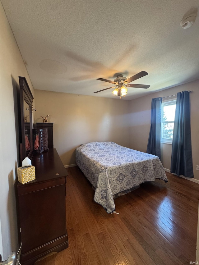 bedroom with hardwood / wood-style flooring, ceiling fan, baseboards, and a textured ceiling