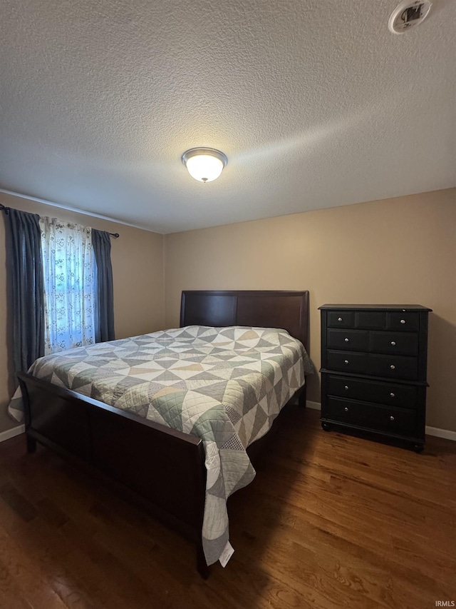 bedroom featuring visible vents, a textured ceiling, baseboards, and dark wood-style flooring