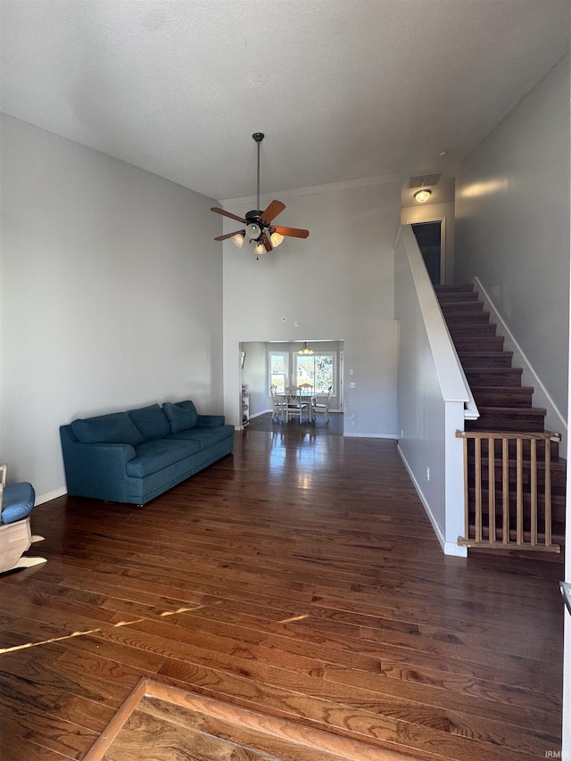 unfurnished living room with stairway, wood finished floors, a ceiling fan, and baseboards