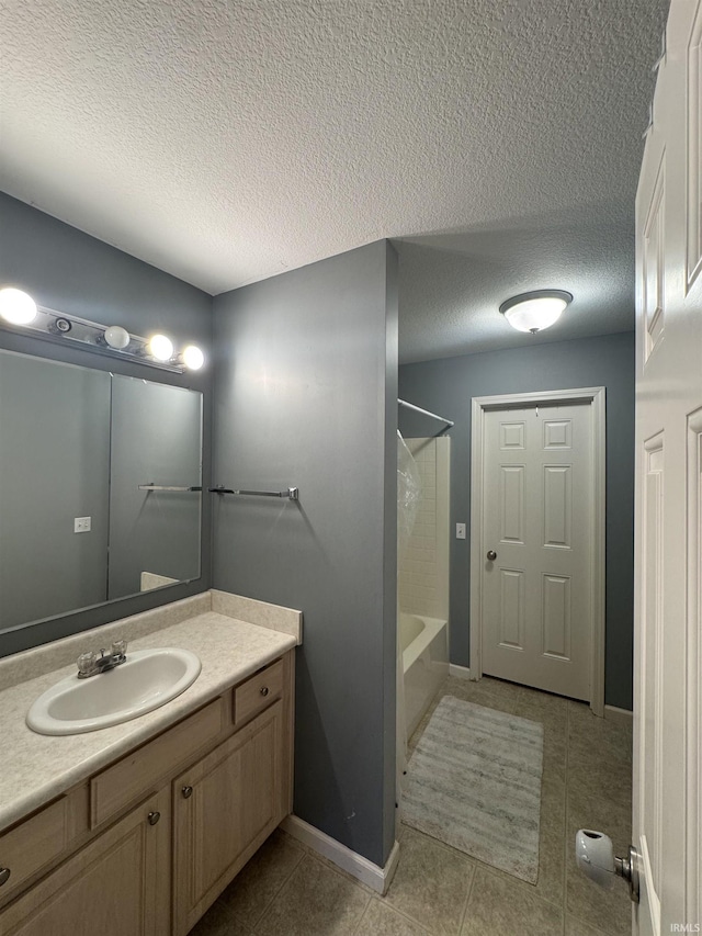 full bath with a textured ceiling, vanity, baseboards, tile patterned floors, and washtub / shower combination