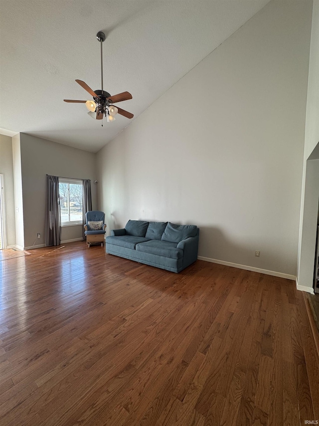 unfurnished living room featuring high vaulted ceiling, dark wood-type flooring, a ceiling fan, and baseboards