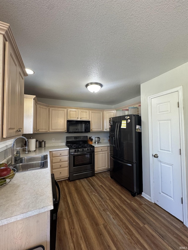 kitchen with light countertops, light brown cabinets, a sink, and black appliances