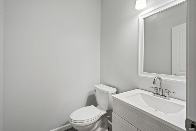 half bathroom featuring vanity, toilet, and baseboards