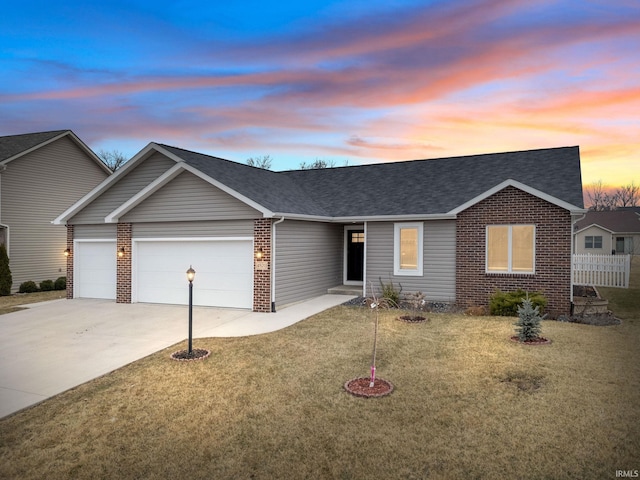 ranch-style house with brick siding, a yard, a shingled roof, a garage, and driveway