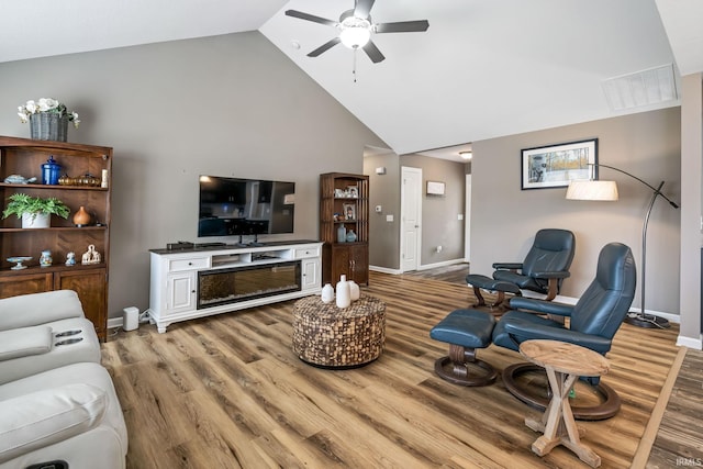 living area with ceiling fan, high vaulted ceiling, light wood-style flooring, visible vents, and baseboards