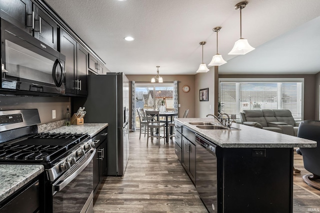 kitchen featuring dishwasher, gas range, dark wood-type flooring, black microwave, and a sink