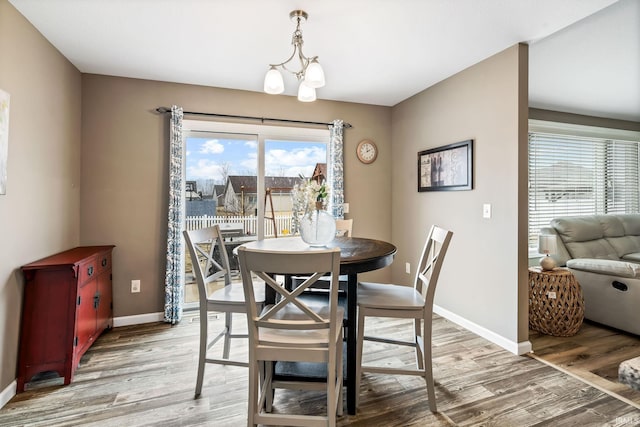 dining area with light wood finished floors, an inviting chandelier, and baseboards