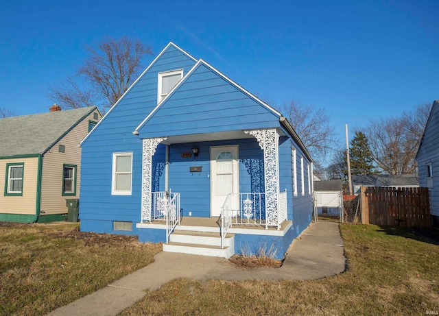 view of front of property with a porch, a front yard, and fence