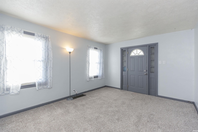 entryway with a textured ceiling, carpet, and baseboards