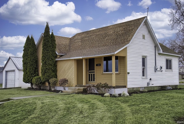 view of front of property featuring a shingled roof, an outdoor structure, and a front lawn