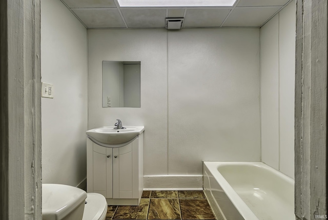 full bath featuring a paneled ceiling, a tub, toilet, and vanity