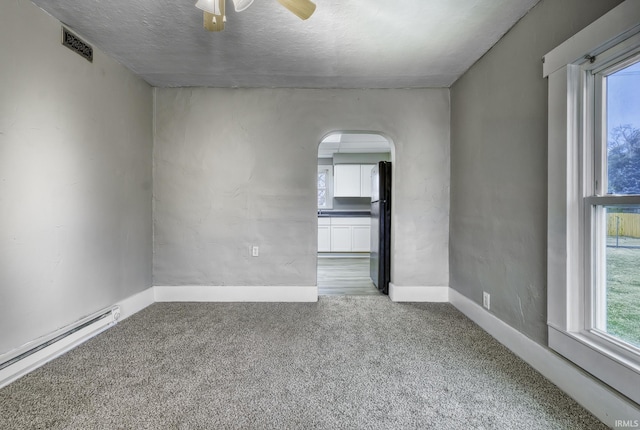 unfurnished room featuring carpet floors, baseboard heating, plenty of natural light, and visible vents