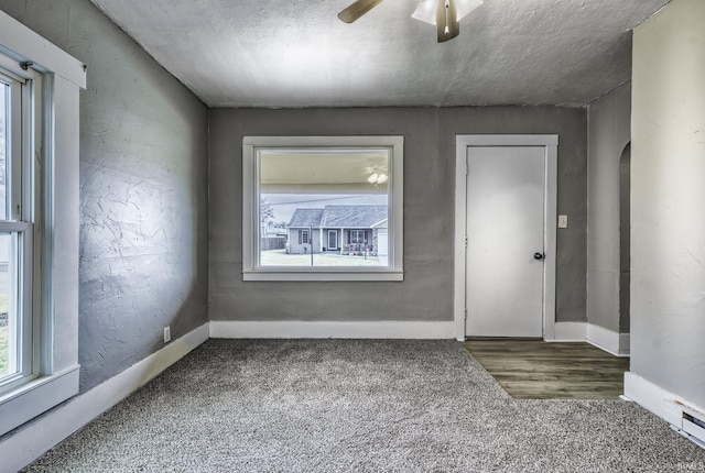 empty room featuring ceiling fan, arched walkways, carpet flooring, and a healthy amount of sunlight