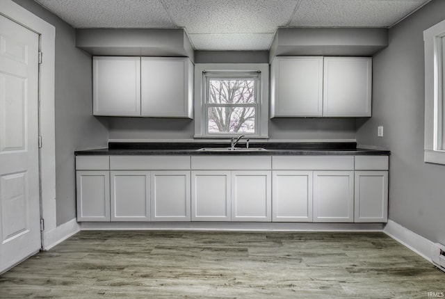 kitchen featuring dark countertops, light wood-type flooring, baseboards, and a sink