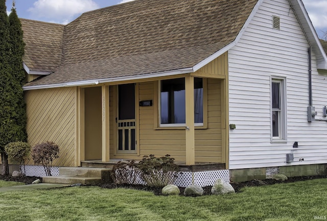 exterior space with roof with shingles and a lawn