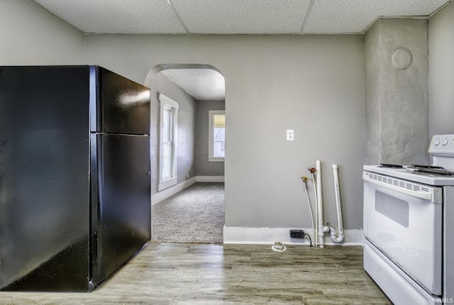 kitchen featuring arched walkways, wood finished floors, freestanding refrigerator, a paneled ceiling, and white range with electric cooktop