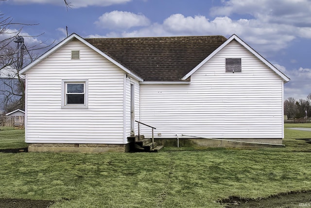 view of side of home featuring entry steps, a yard, and a shingled roof