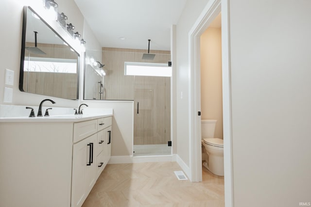 bathroom with toilet, visible vents, vanity, baseboards, and a stall shower