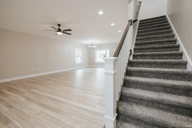 stairway featuring baseboards, ceiling fan with notable chandelier, wood finished floors, and recessed lighting