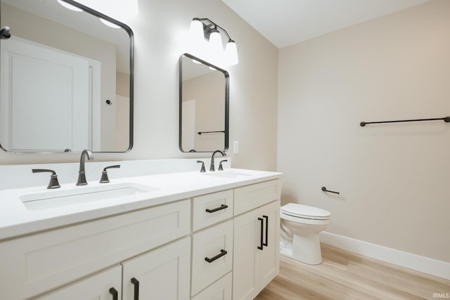 bathroom with double vanity, wood finished floors, a sink, and toilet