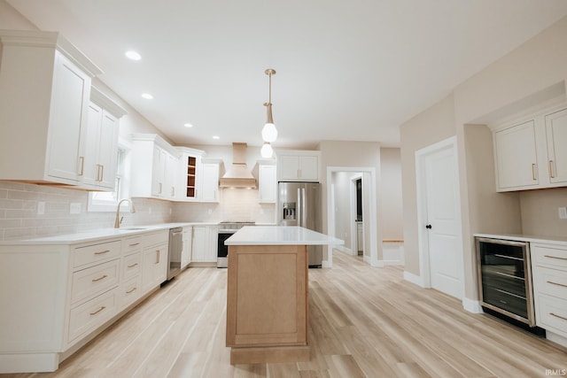 kitchen with beverage cooler, light wood-style flooring, custom range hood, stainless steel appliances, and a sink