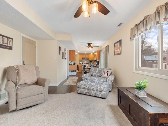 carpeted living room featuring visible vents, ceiling fan, and baseboards