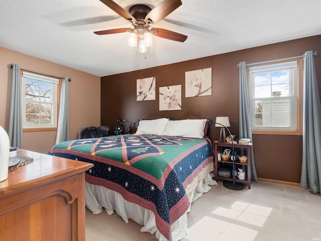 bedroom featuring multiple windows, baseboards, a textured ceiling, and light colored carpet