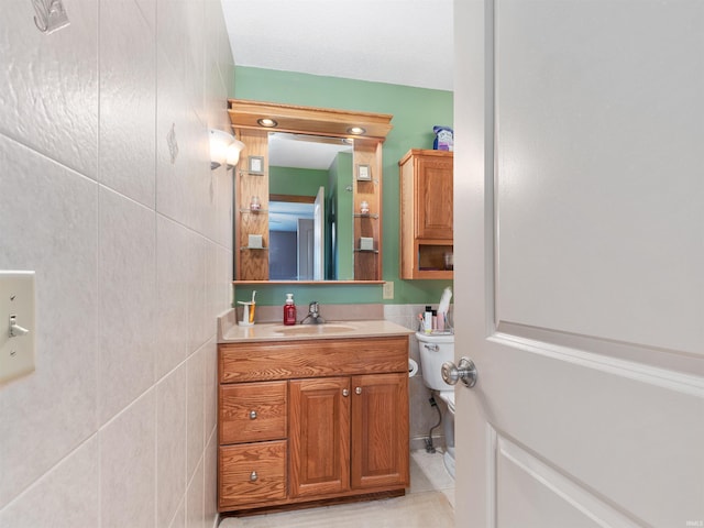 half bathroom with toilet, tile walls, vanity, and tile patterned floors