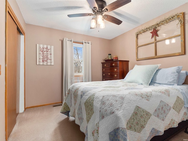 bedroom with a closet, light colored carpet, visible vents, a textured ceiling, and baseboards